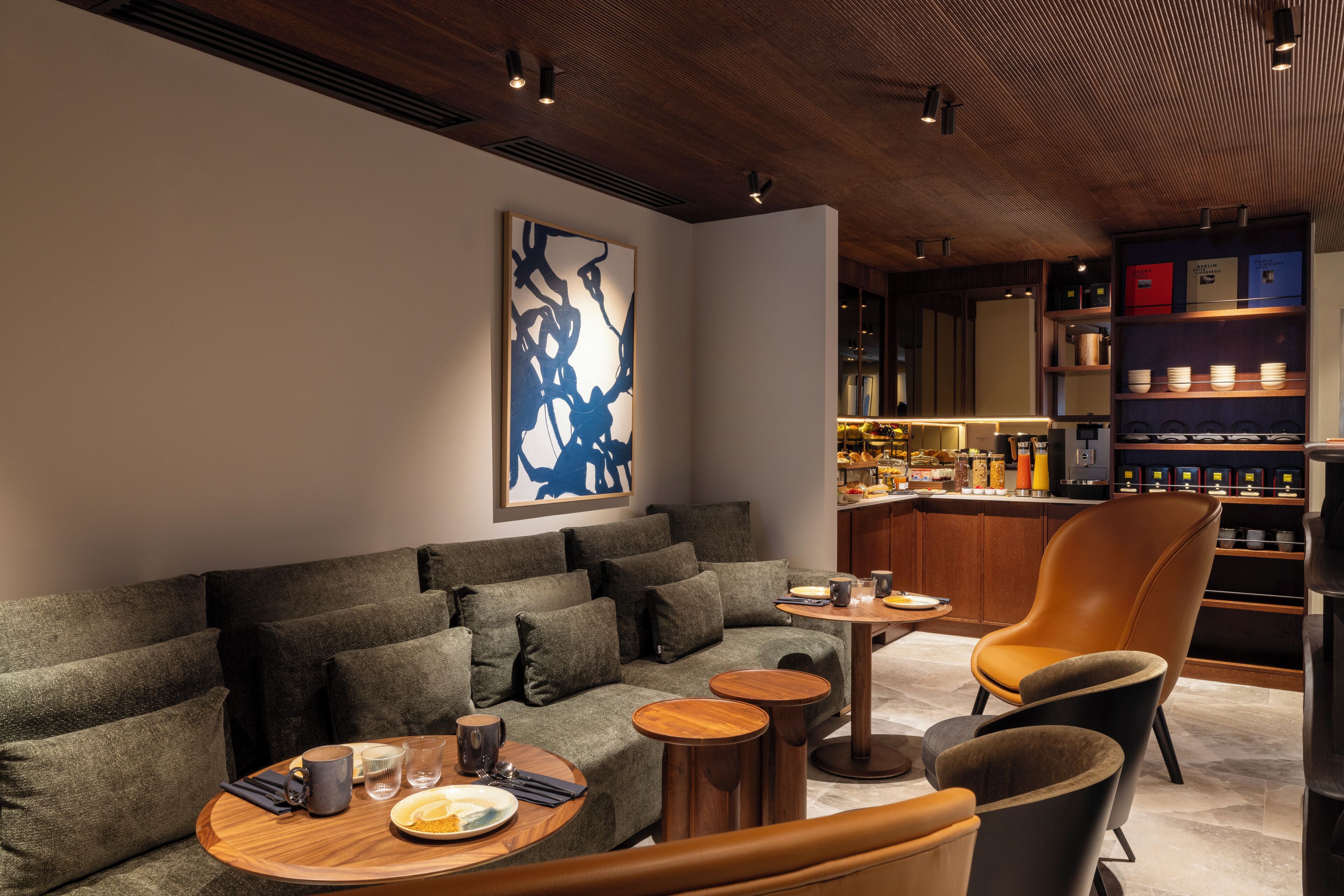 A modern lounge area with a sofa, armchairs, and a small bar area.