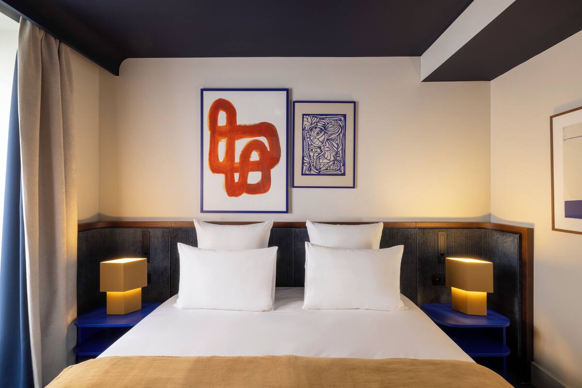 A double bed with two nightstands, each with a lamp, in a hotel room.