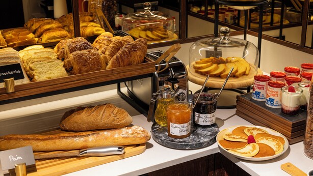 Een ontbijtbuffet met verschillende broden, gebak en jam.