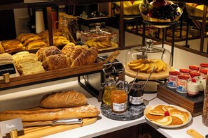 A breakfast buffet with various breads, pastries, and jams. - Hôtel Gabbie (Paris)