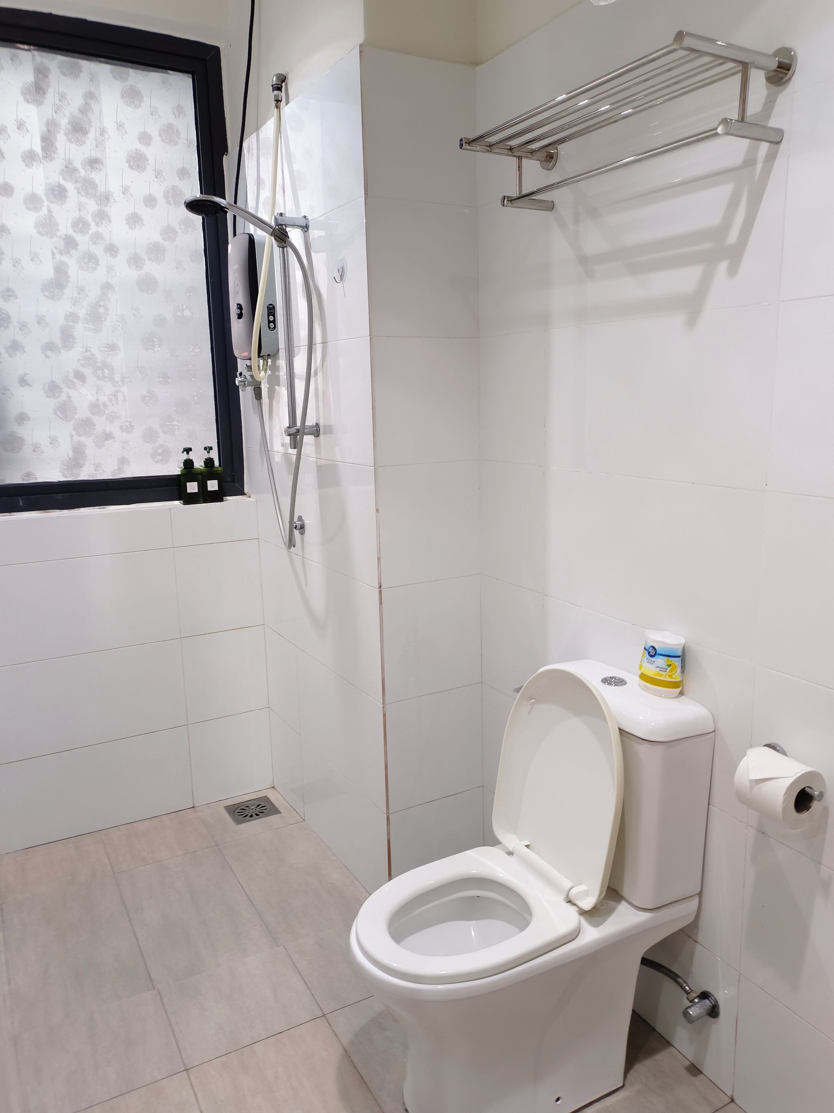 Een badkamer met toilet, douche en raam met een geëtste versiering.