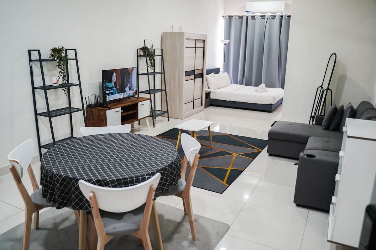 A modern living room with a dining area, a sofa, a TV, and a wardrobe.