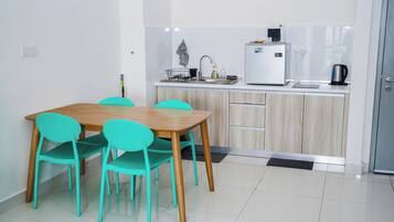 Een moderne keuken met een houten tafel en turquoise stoelen, een witte koelkast en een waterkoker op het aanrecht.