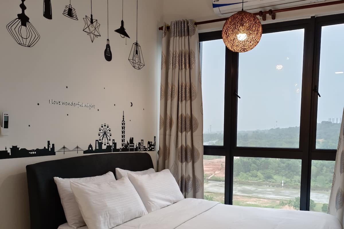 A bedroom with a bed, multiple hanging lights, a cityscape wall decal, a large window with a view, and an air conditioning unit.