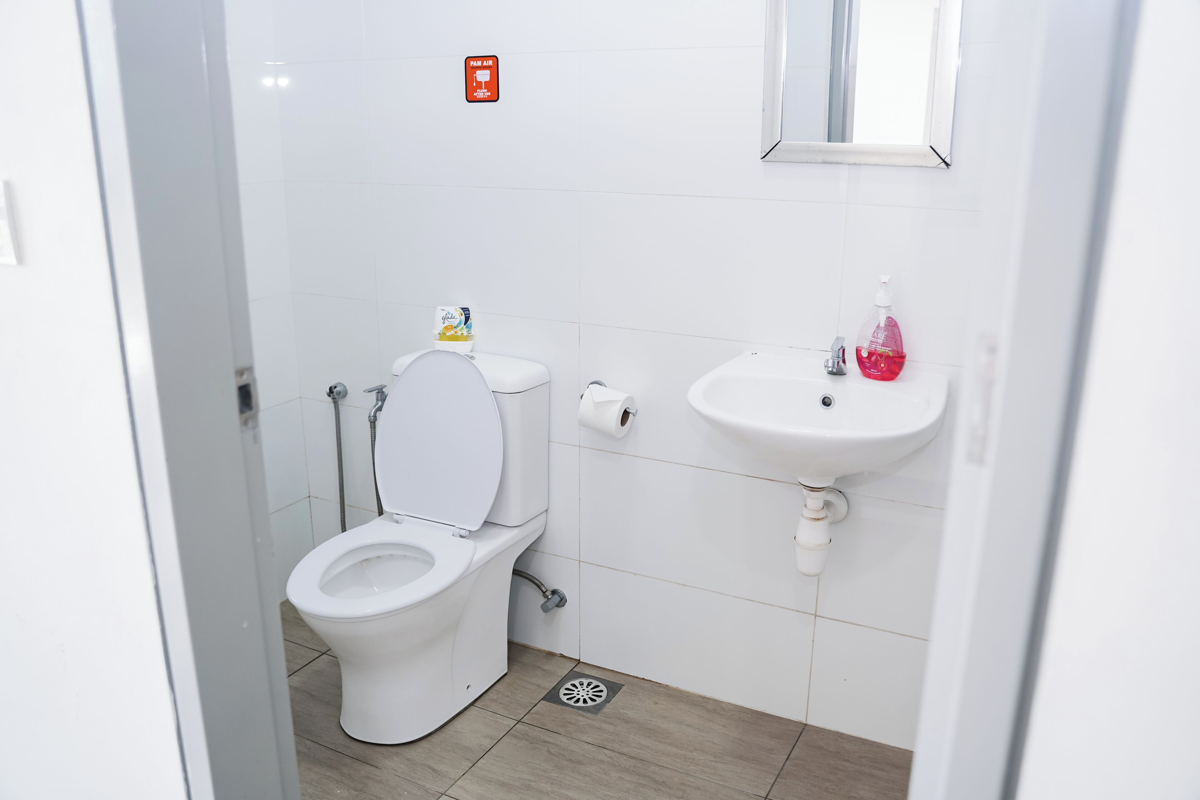 A small, clean bathroom with a toilet, sink, and mirror.