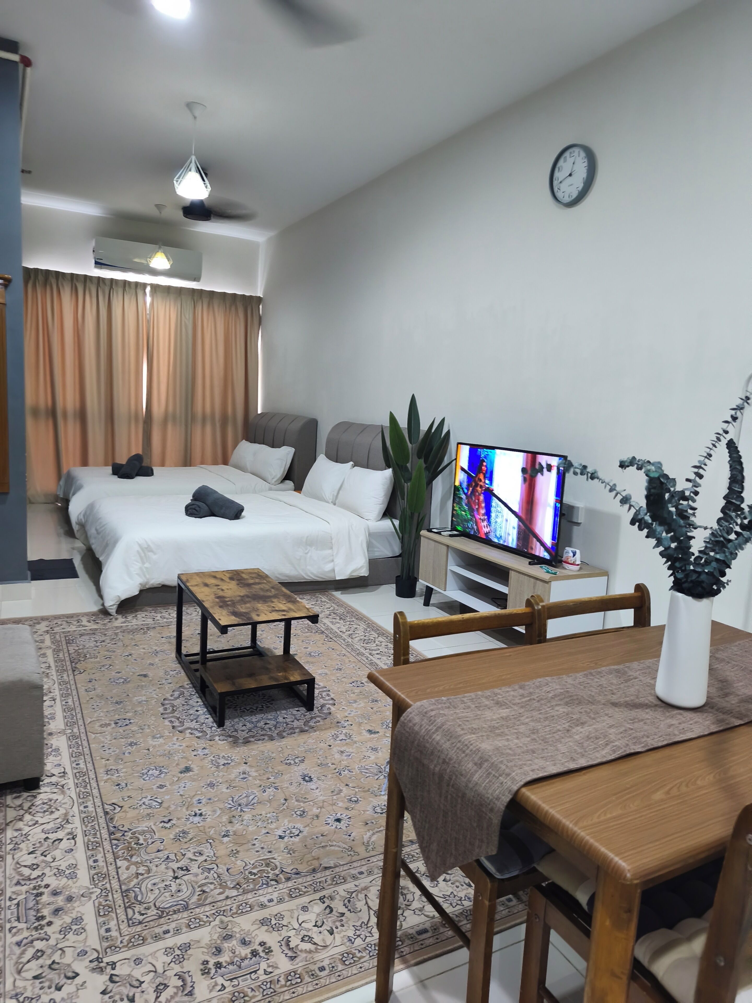 A modern living room with a sofa, a wooden coffee table, a TV, and a dining area with a table and chairs.