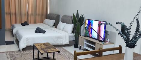 Una sala de estar moderna con un sofá, una mesa de centro de madera, un televisor y un comedor con una mesa y sillas.