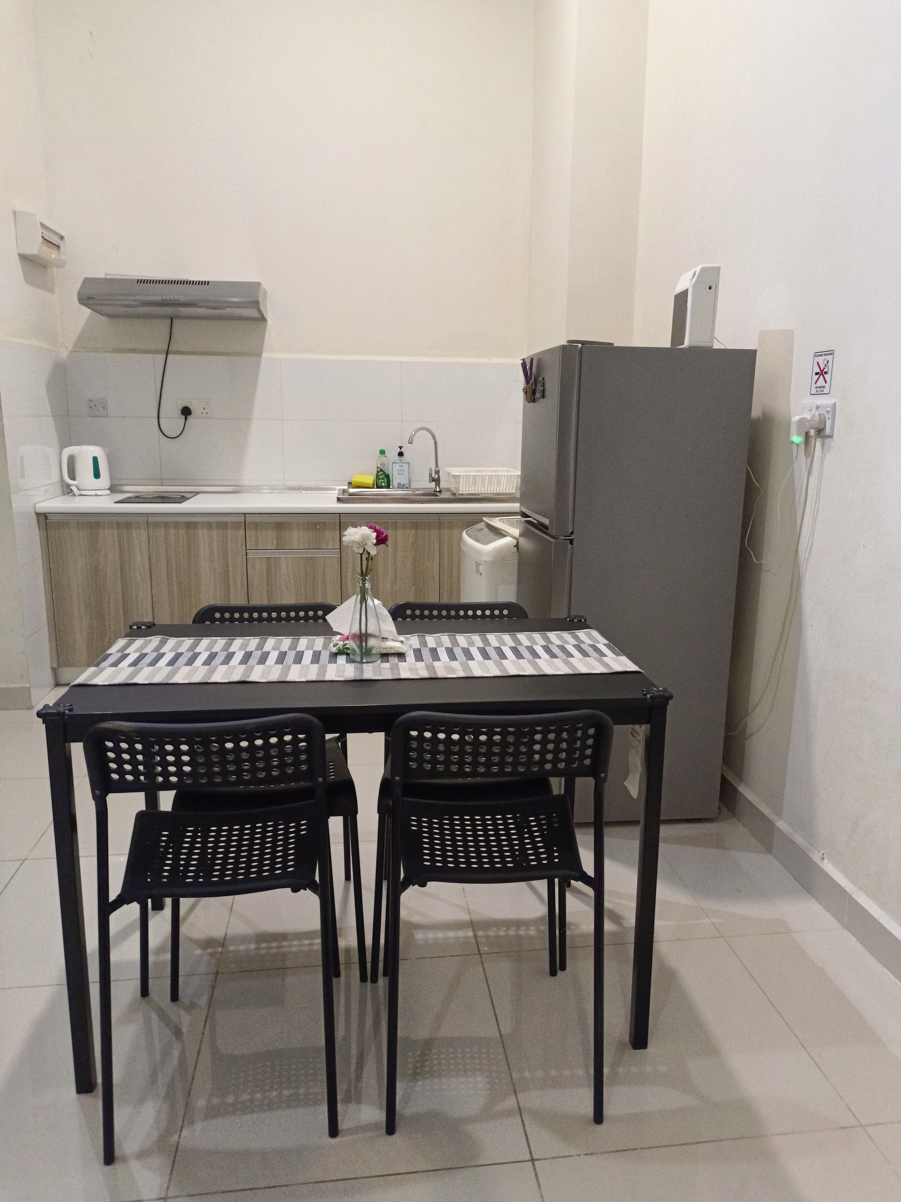 A compact kitchen with a dining table, chairs, a refrigerator, and a sink.
