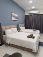 A hotel room with two beds, a large window with curtains, an air conditioning unit, and a painting on the wall.