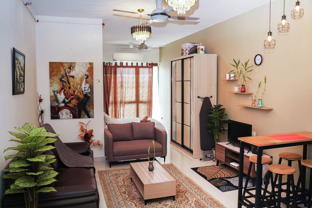 A living room with a sofa, coffee table, TV, and a dining area with stools.