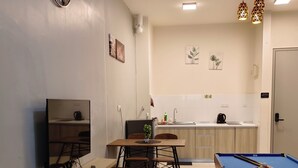 A modern living room with a flat-screen TV, a pool table, and a dining area with a wooden table and chairs. - KLIA AIRPORT HOMESTAY (Sepang)