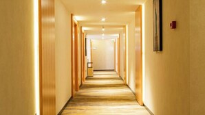 A hotel hallway with a carpeted floor, wooden walls, and a framed picture on the right wall. - Tianyi Art Hotel (Minhou)