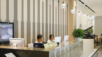 A reception desk with a computer, a television, and a plant.