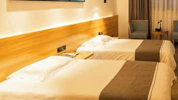 A hotel room with two beds, a wooden headboard, a small table with a phone, and a chair.