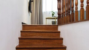 A wooden staircase with a handrail and a small table with a plant in the background. - Tianyi Art Hotel (Minhou)