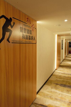 A hotel hallway with wooden paneling and a carpeted floor.