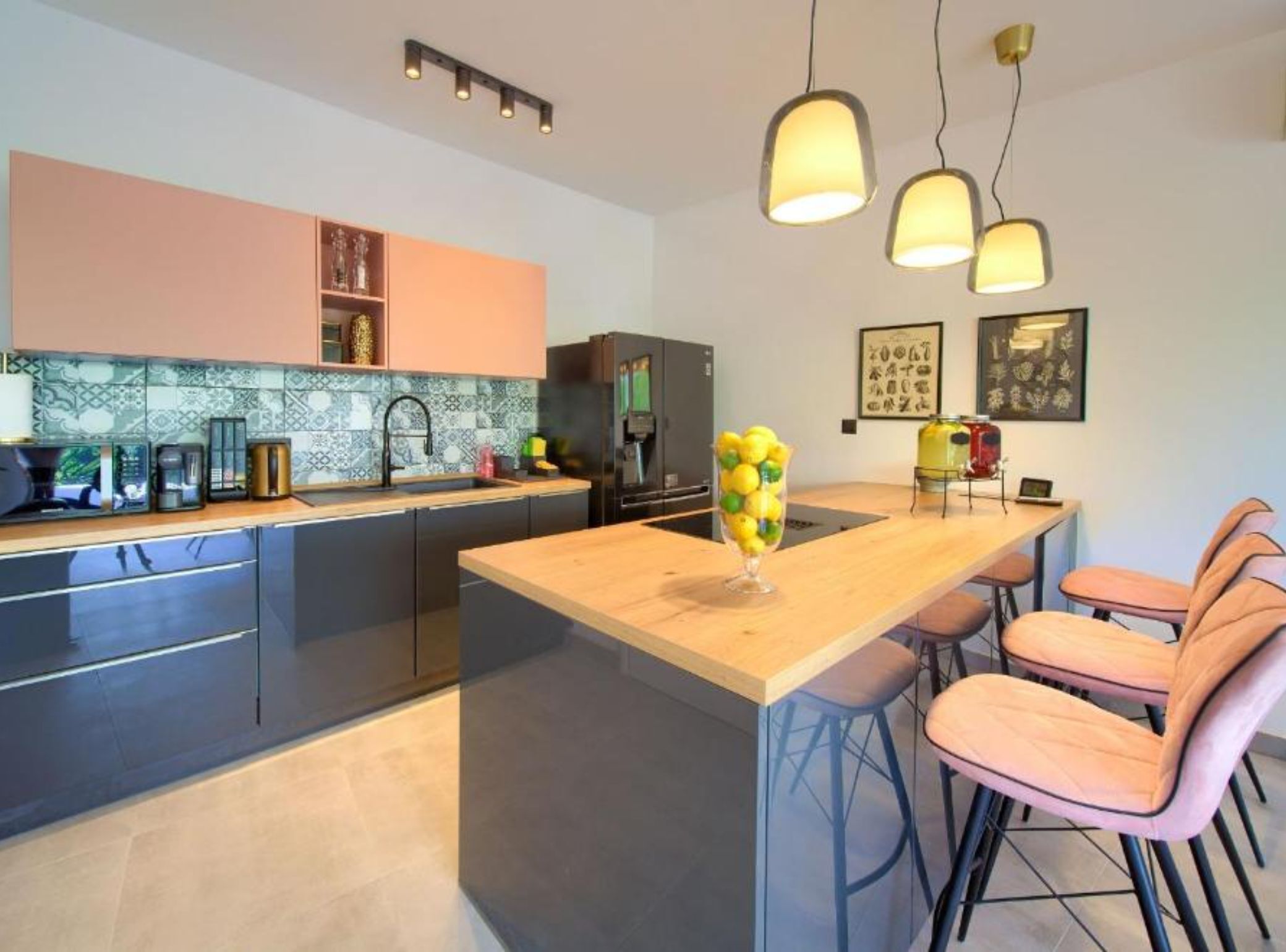 Une cuisine moderne dotée d’un îlot central, de tabourets de bar et de luminaires suspendus.