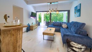 A modern living room with a blue sofa, a wooden coffee table, and a TV mounted on the wall. - Wellness Villa (Vinodol)
