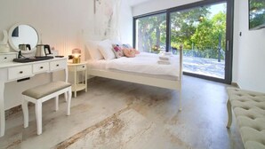 A bedroom with a large bed, a bedside table, a mirror, and a bench. There is a large window providing a view of greenery outside. - Wellness Villa (Vinodol)