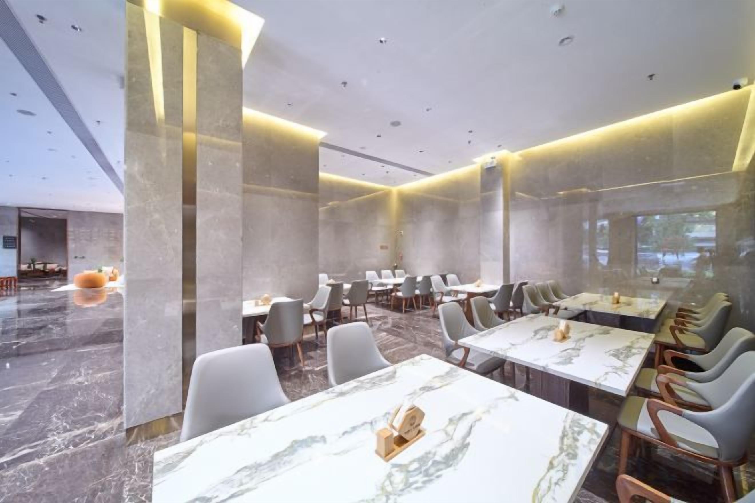 A modern hotel dining area with marble tables, comfortable seating, and ambient lighting.