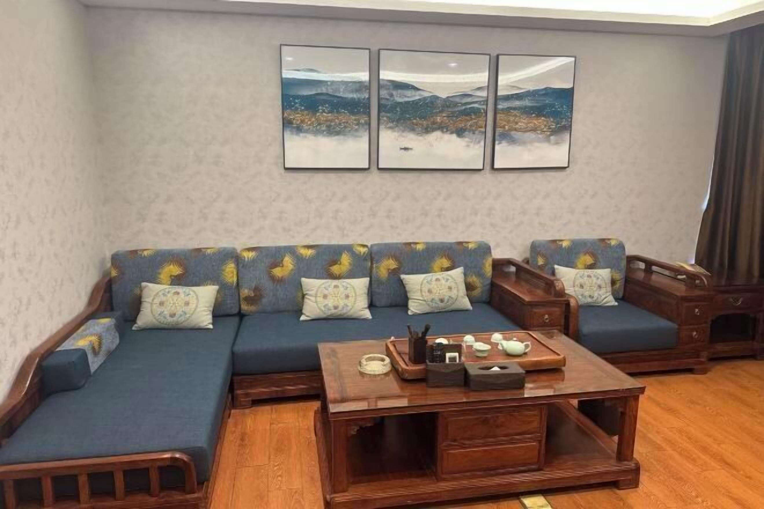 Een woonkamer met een zithoek, een salontafel en drie ingelijste foto’s aan de muur.