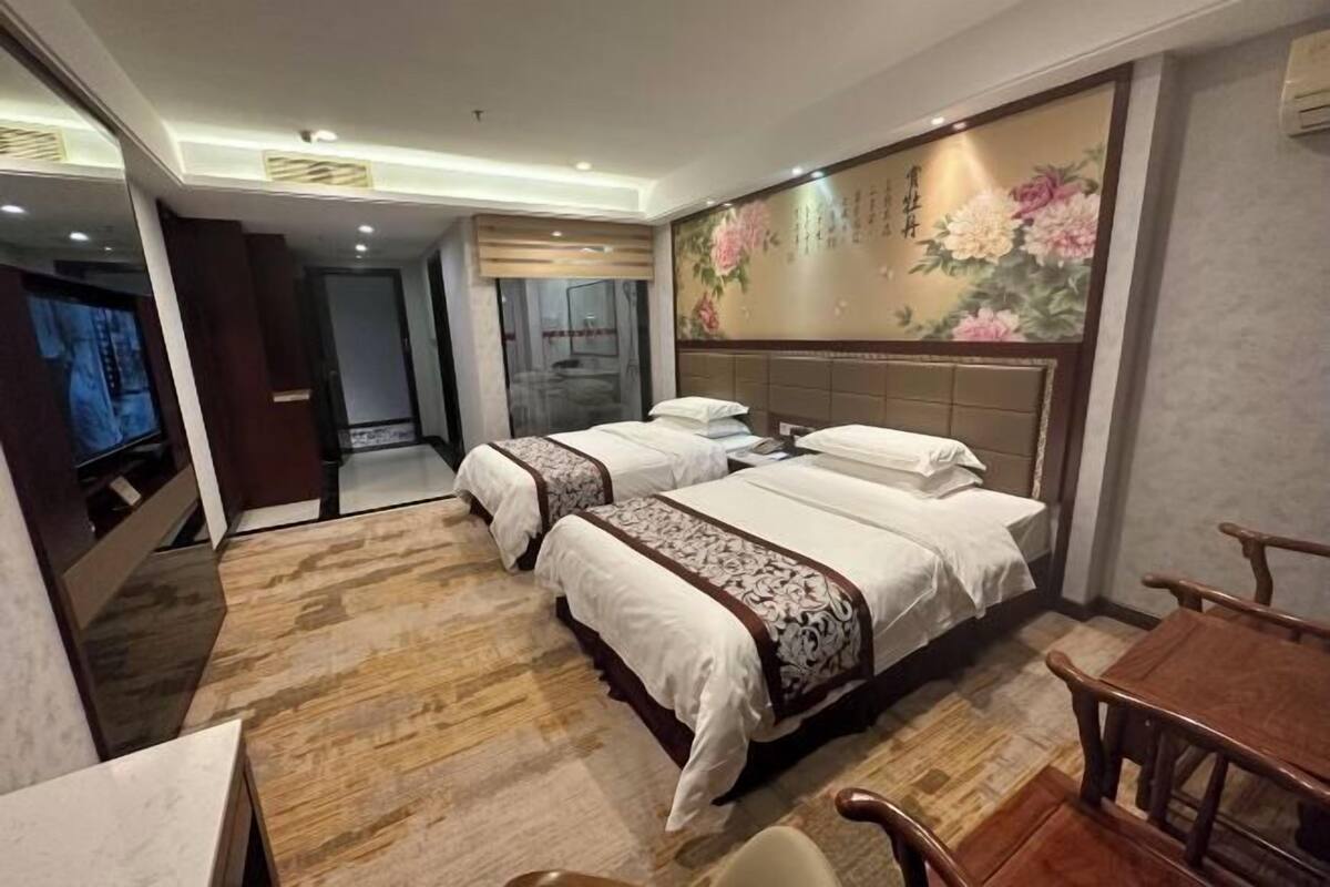 Ein Hotelzimmer mit zwei Betten, Holzboden, einem Esstisch und einem Fernseher.
