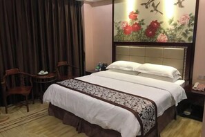 A hotel room with a bed, a desk, a chair, and a painting on the wall. - Jiangmen Xinhui Chenpi Redwood Hotel (Xinhui Sports Center) (Jiangmen)