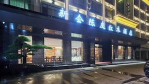 A building with illuminated signage, a well-lit entrance, and a visible storefront with large windows. - Jiangmen Xinhui Chenpi Redwood Hotel (Xinhui Sports Center) (Jiangmen)