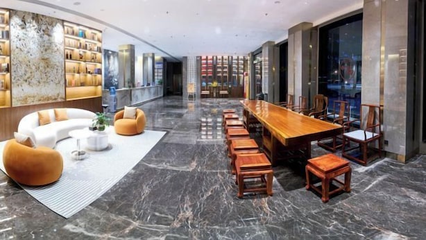 A modern hotel lobby with a curved seating area, a long wooden dining table, and a marble floor. - Jiangmen Xinhui Chenpi Redwood Hotel (Xinhui Sports Center) (Jiangmen)
