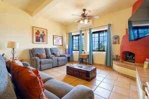 Sala de estar com sofá, lareira e ventilador de teto.