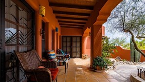 A covered patio with wicker furniture, a tiled floor, and a cactus in the background. - Casa Richy - El Dorado Ranch Rental (San Felípe)