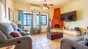 A living room with a sofa, a fireplace, a television, and a ceiling fan. - Casa Richy - El Dorado Ranch Rental (San Felípe)