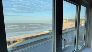 A view from a window overlooking a beach with a road and a barrier. - Les Fregates (Veulettes-sur-Mer)