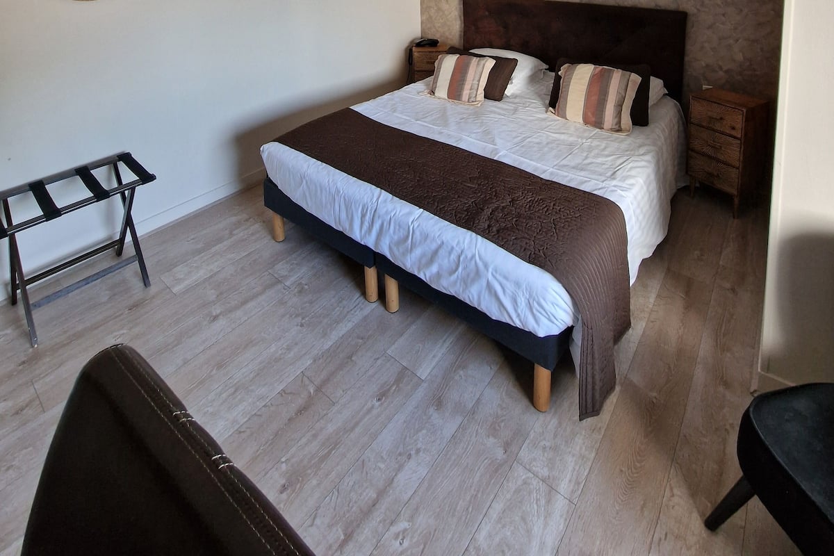 Une chambre à coucher avec un grand lit, une table de chevet, une lampe, un miroir et un luminaire suspendu.