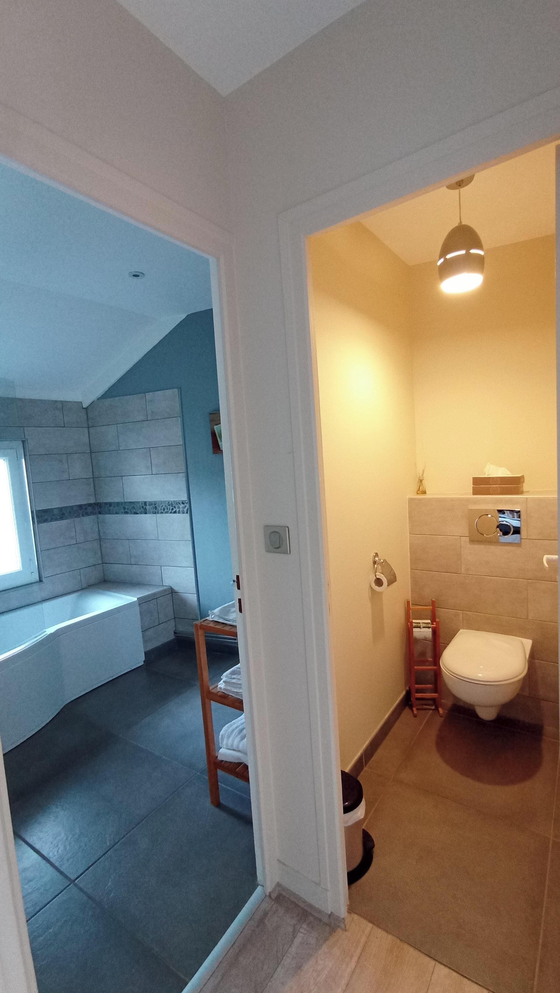 A modern bathroom with a toilet, sink, and shower area. There is a small window and a towel rack.