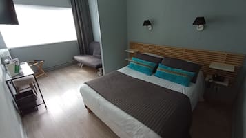 Een hotelkamer met een bed, nachtkastjes, een bureau, een stoel en een raam met gordijnen.