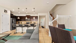 A modern kitchen with dark cabinets, a stainless steel refrigerator, and a microwave.