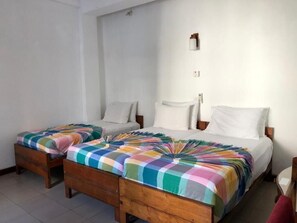 A room with two beds, each with a colorful checkered bedspread and white pillows.