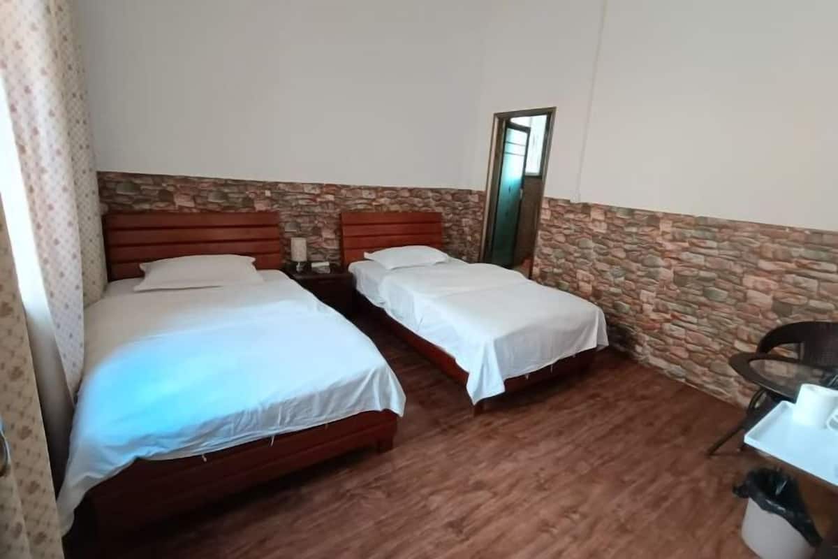 A room with two beds, a small table, and a mirror.