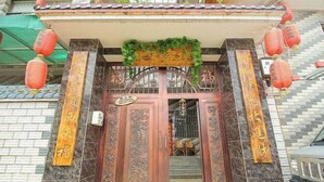 A traditional wooden gate with intricate carvings and Chinese characters, flanked by red lanterns and a green decorative arch. - Shizong Donglai Inn (Shizong)
