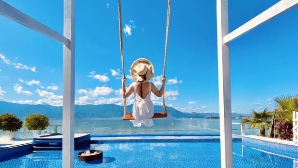 A woman on a swing over a pool with a mountain view. - Erhai Lake View Resort Hotel Yuebo Jingyi (Dali City)