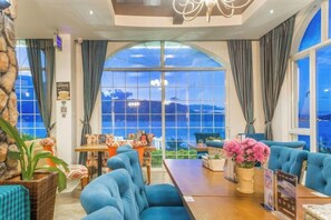 A hotel room with a large arched window, a seating area with blue sofas, and a dining table. - Erhai Lake View Resort Hotel Yuebo Jingyi (Dali City)