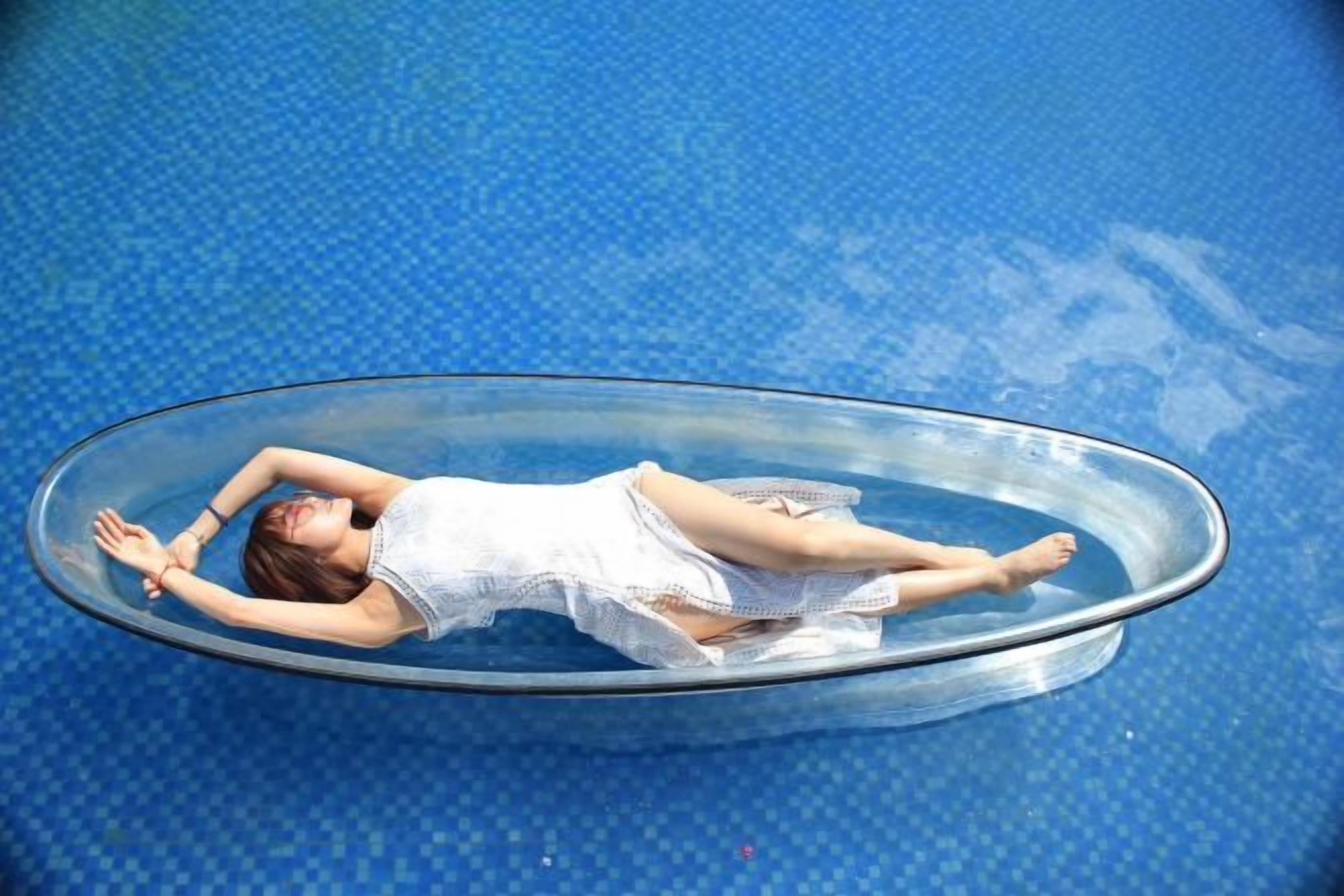 Eine Person liegt in einem klaren, ovalen Pool.