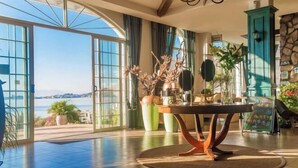A spacious room with a large window overlooking a body of water, a wooden table with a vase of flowers, and a teal cabinet. - Erhai Lake View Resort Hotel Yuebo Jingyi (Dali City)
