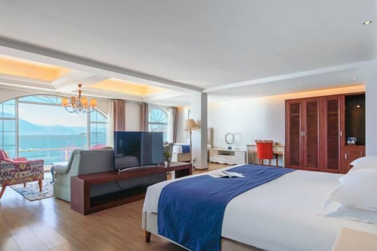 Habitación de hotel con una cama grande, televisión, escritorio y vista al mar.