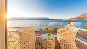A balcony with wicker chairs and a table, overlooking a calm body of water and distant mountains. - Erhai Lake View Resort Hotel Yuebo Jingyi (Dali City)