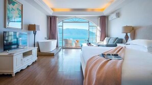 A modern hotel room with a large bed, a TV, a bathtub, and a view of the sea. - Erhai Lake View Resort Hotel Yuebo Jingyi (Dali City)
