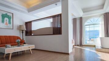 Una habitación de hotel moderna con un ventanal grande, un sofá, una mesita auxiliar y un espejo decorativo.