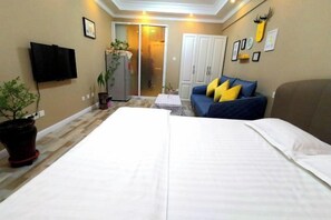 A hotel room with a bed, a sofa, a television, a wardrobe, and a door leading to a balcony. - Fashion Express Short-term Rental Apartment (Zhuanghe Xintiandi Huafu Branch) (Zhuanghe)