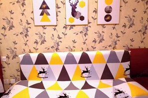 A bed with a geometric patterned bedspread featuring deer silhouettes and the text "Running deer." - Fashion Express Short-term Rental Apartment (Zhuanghe Xintiandi Huafu Branch) (Zhuanghe)